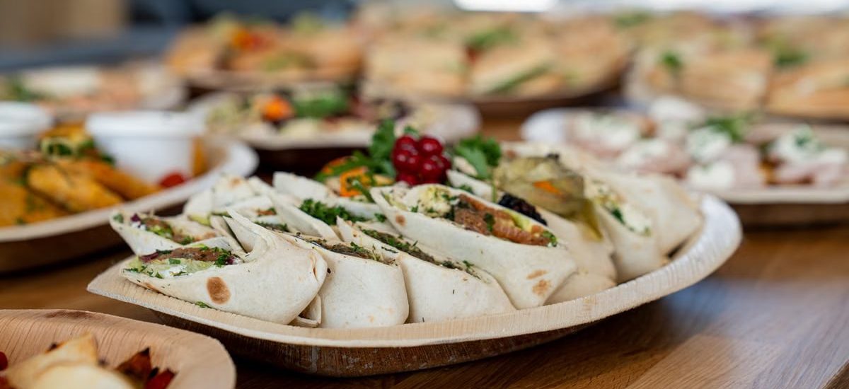 A wooden platter of assorted vegetarian wraps with fresh ingredients, perfect for parties.