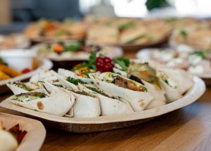 A wooden platter of assorted vegetarian wraps with fresh ingredients, perfect for parties.
